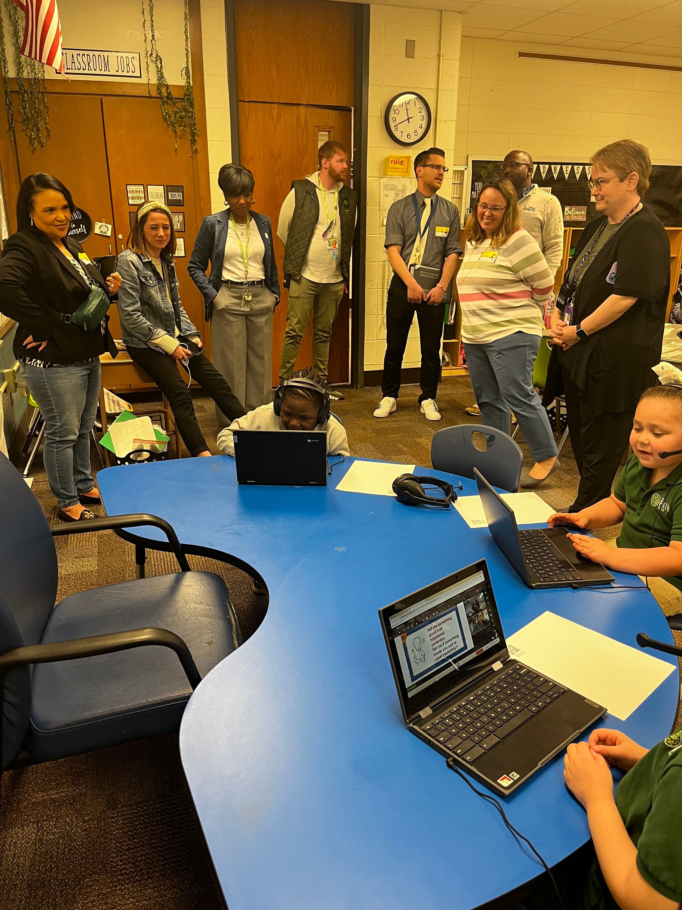 adults looking at children as they engage with laptops