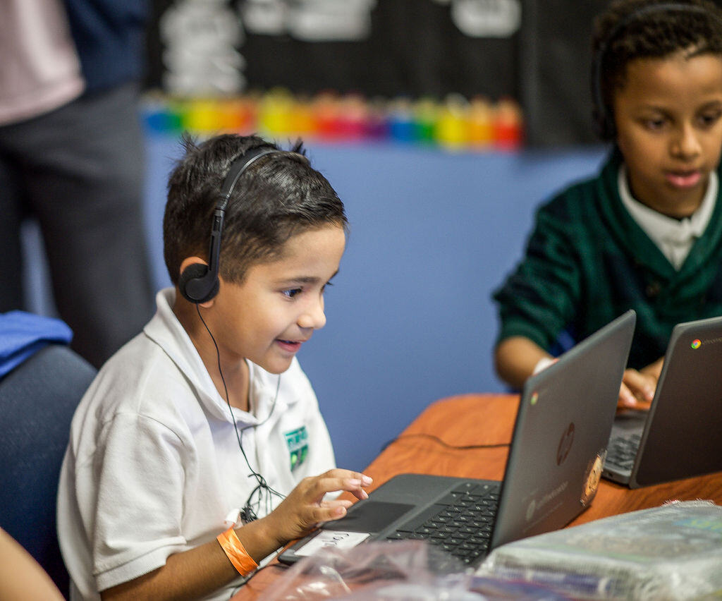 young boy wearing headphones and looking at a laptop screen