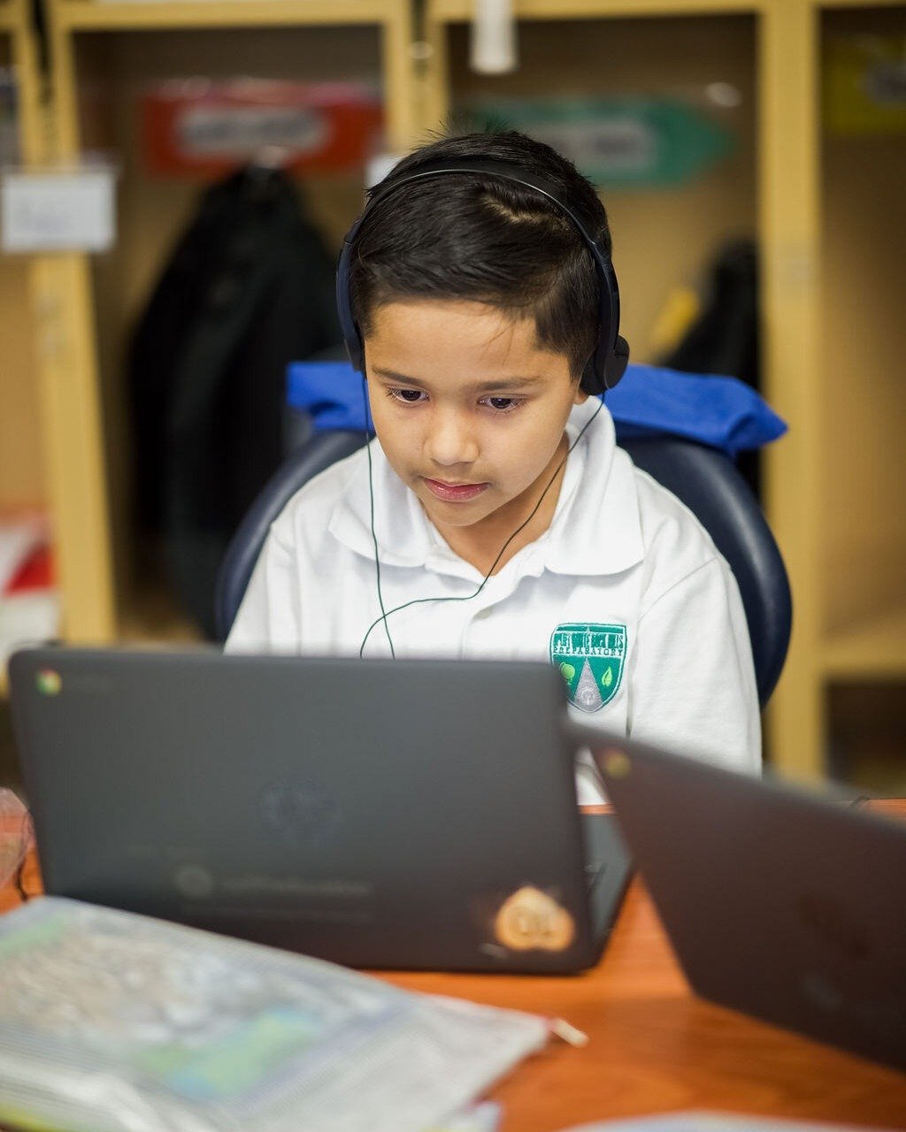 young boy wearing headphones and looking at a laptop young boy wearing headphones and looking at a laptop